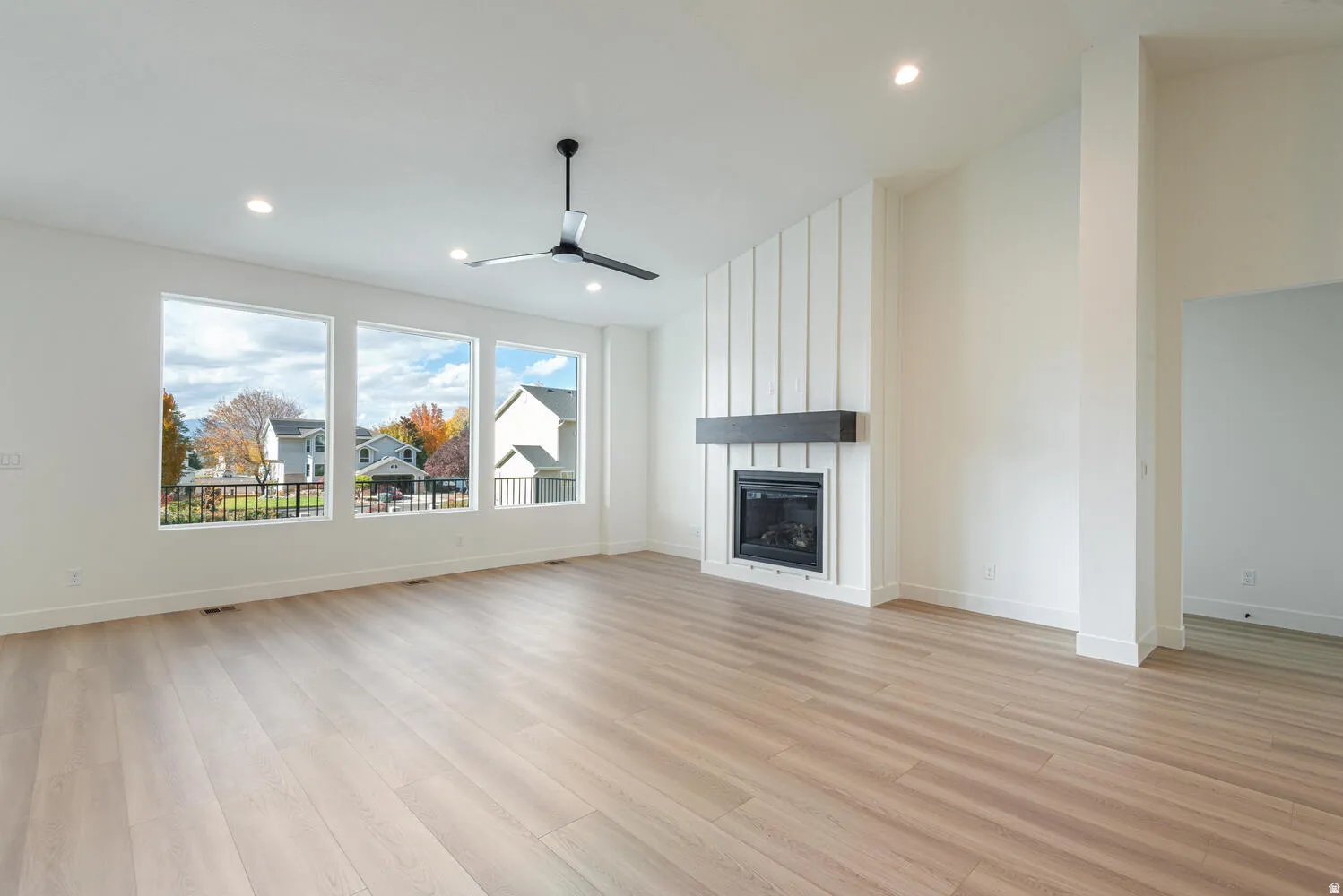 Unfurnished living room featuring a ceiling fan, a large fireplace, light wood-style floors, recessed lighting, and lofted ceiling