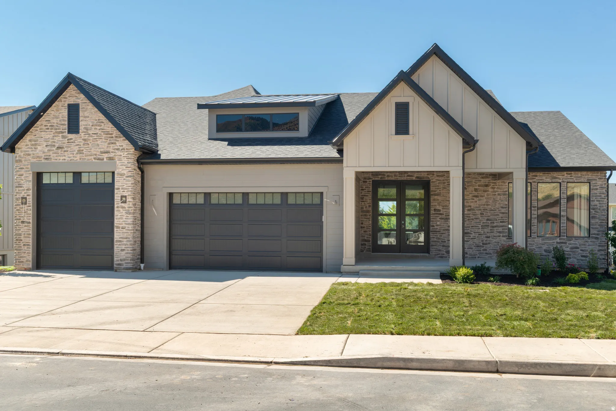 Modern inspired farmhouse featuring driveway, an attached garage, a shingled roof, a front lawn, and board and batten siding