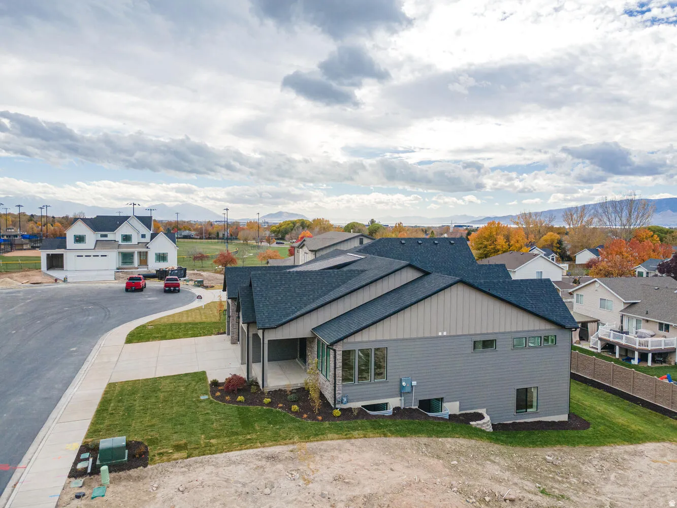 View of side of home featuring roof with shingles, a residential view, a lawn, board and batten siding, and a mountain view