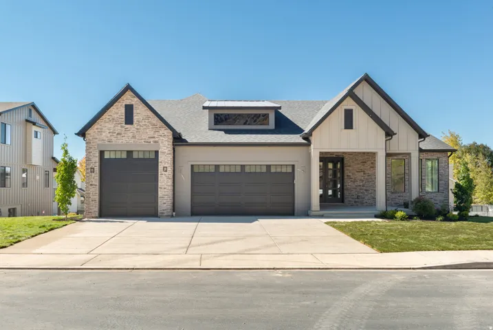 Modern farmhouse with a garage, concrete driveway, a front yard, board and batten siding, and roof with shingles