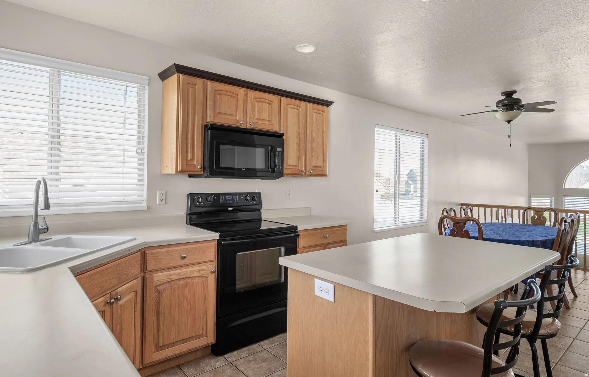 Kitchen with black appliances, a breakfast bar area, a kitchen island, and light countertops
