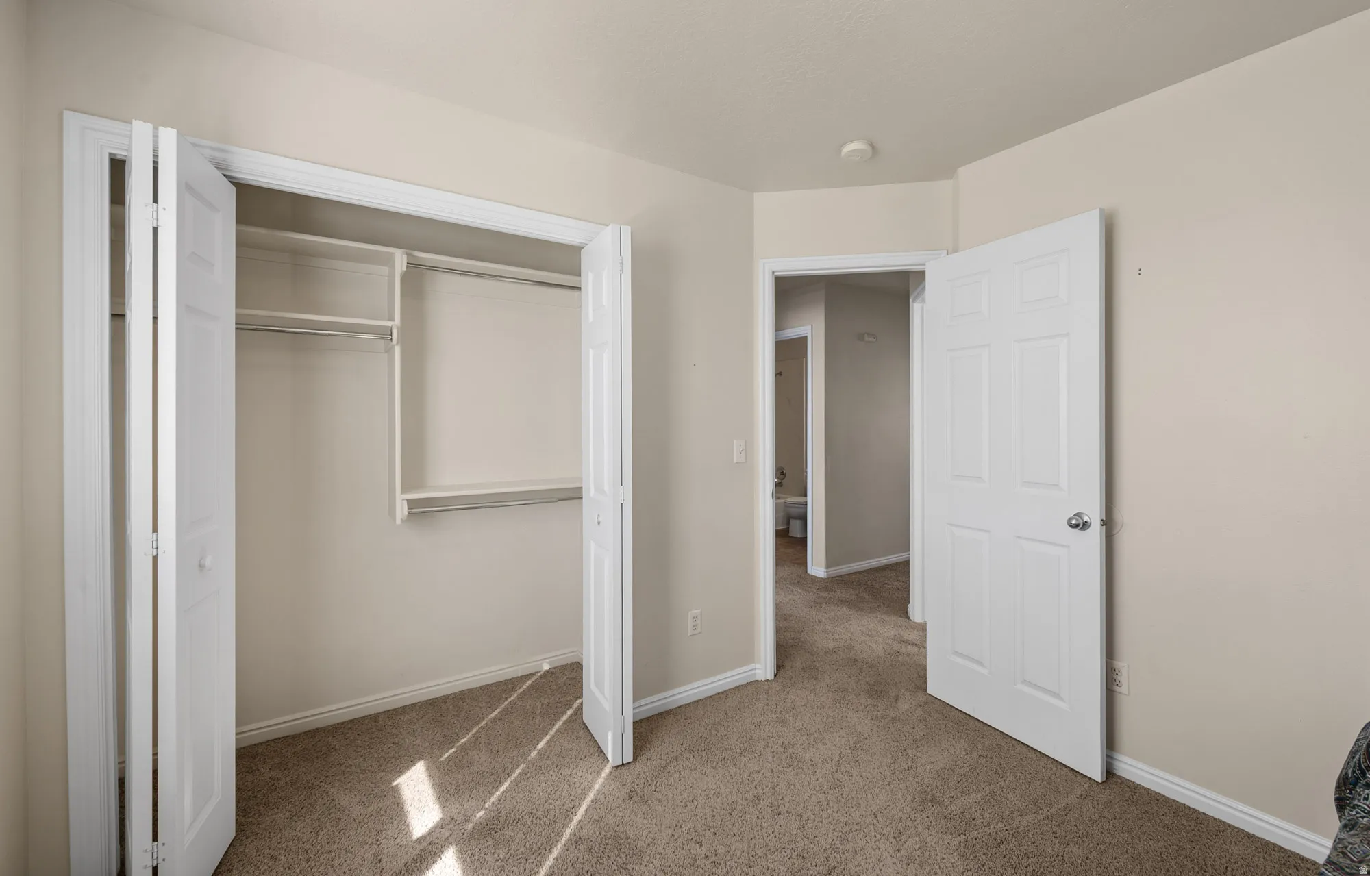 Bedroom with light colored carpet and a closet