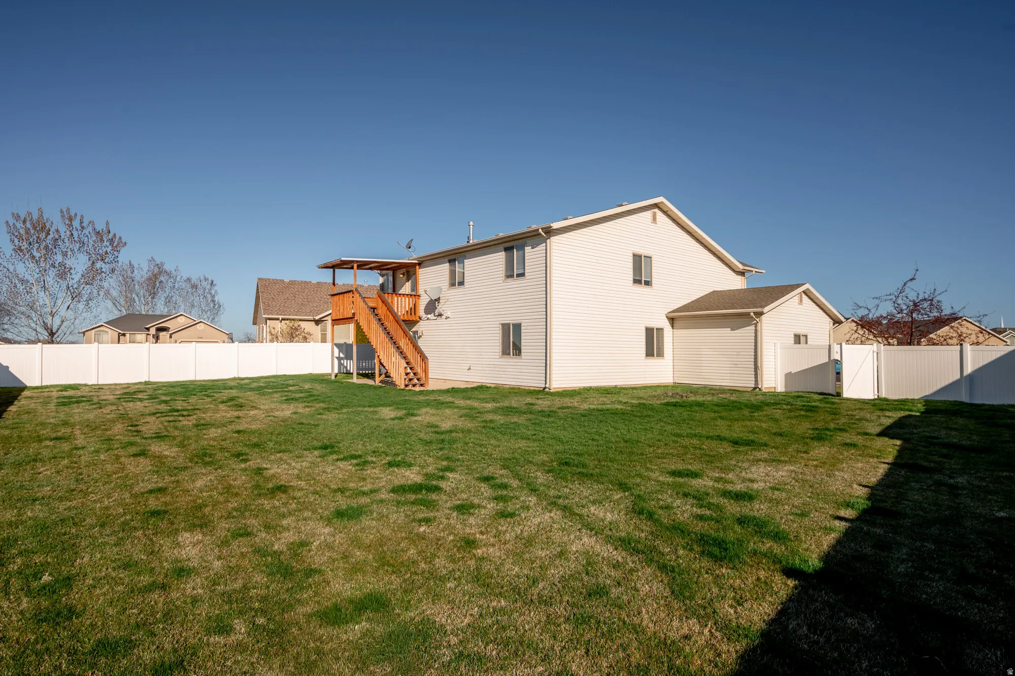 Rear view of property featuring a fenced backyard, a gate, and a deck
