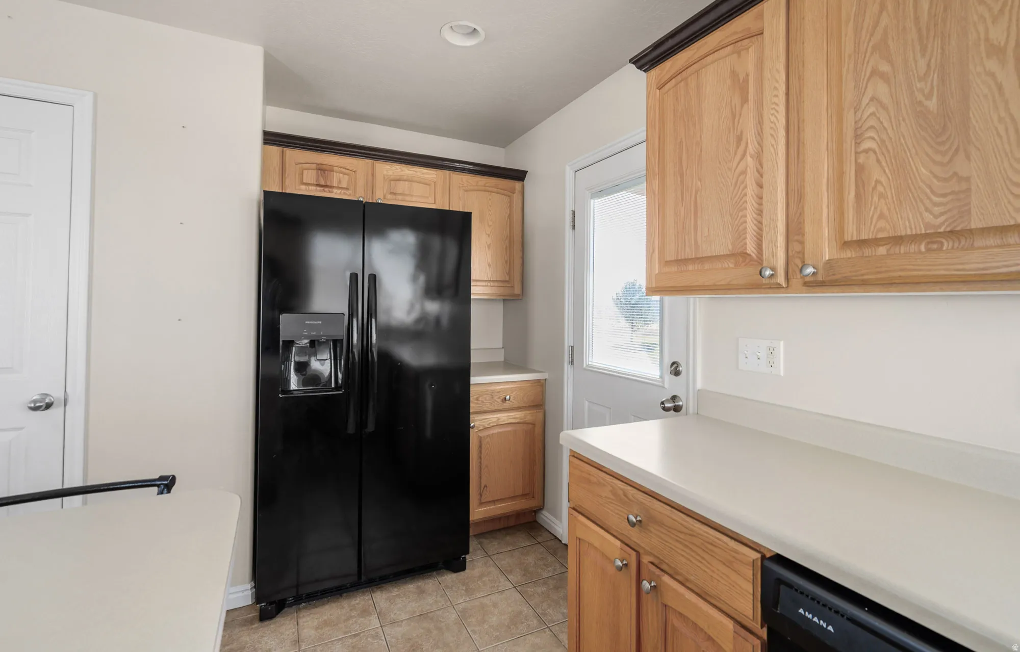 Kitchen with black appliances, light countertops, and light tile patterned floors
