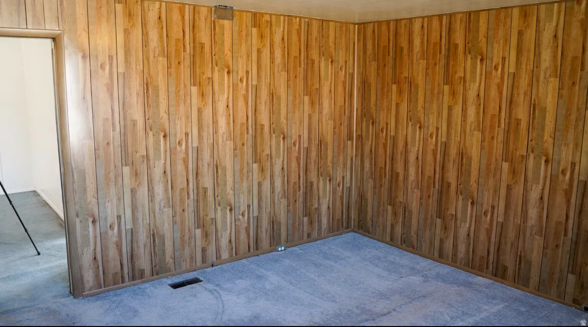Carpeted empty room featuring wooden walls