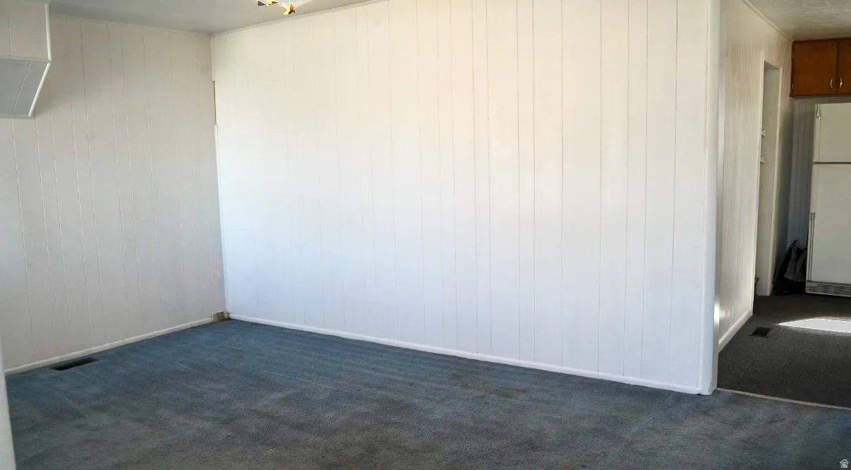 Empty room featuring dark carpet and wood walls