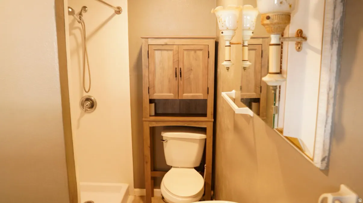 Full bath featuring a shower stall and toilet