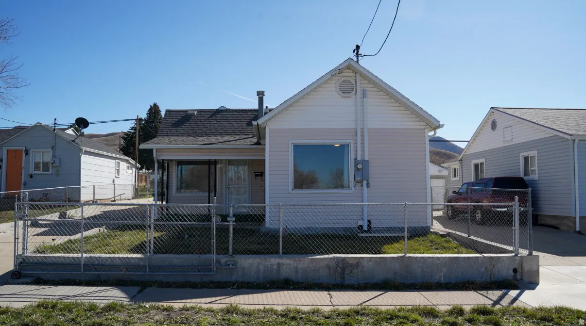 View of front of property with a fenced front yard, a gate, and covered porch