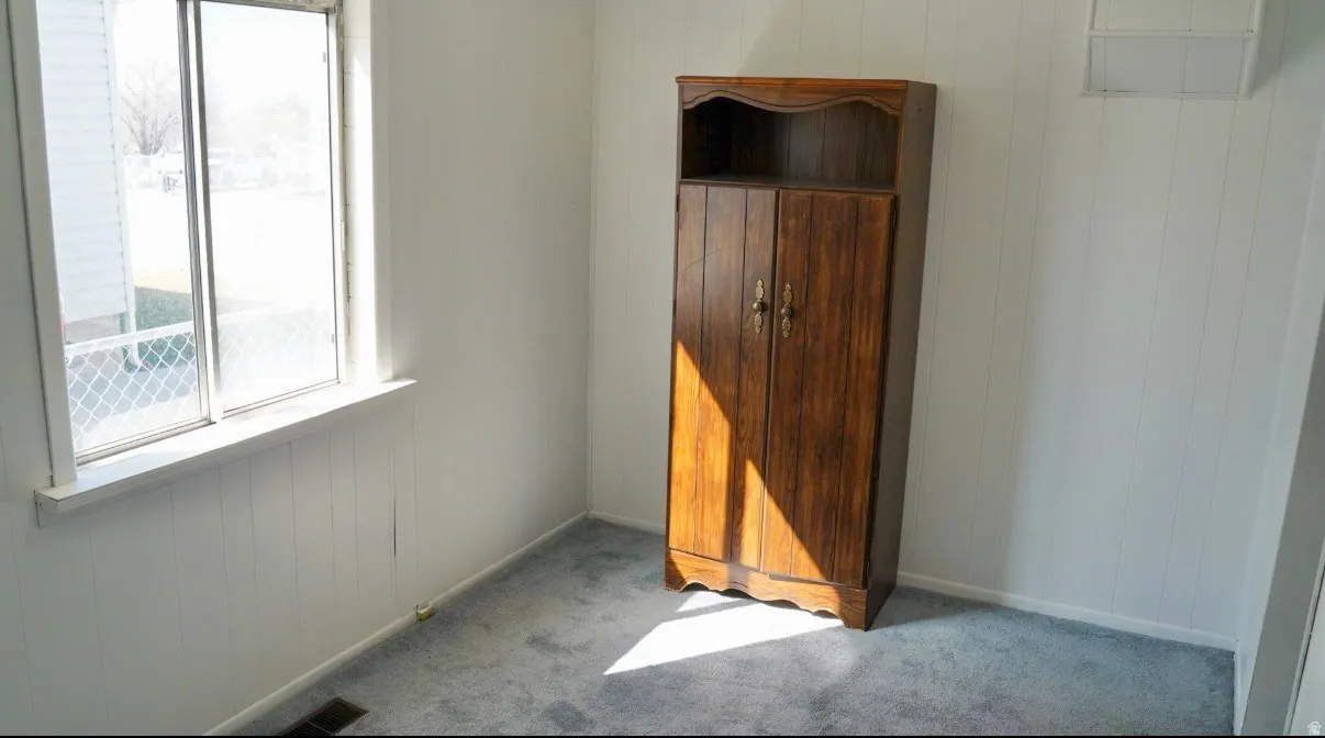 Unfurnished bedroom with wood walls and light carpet