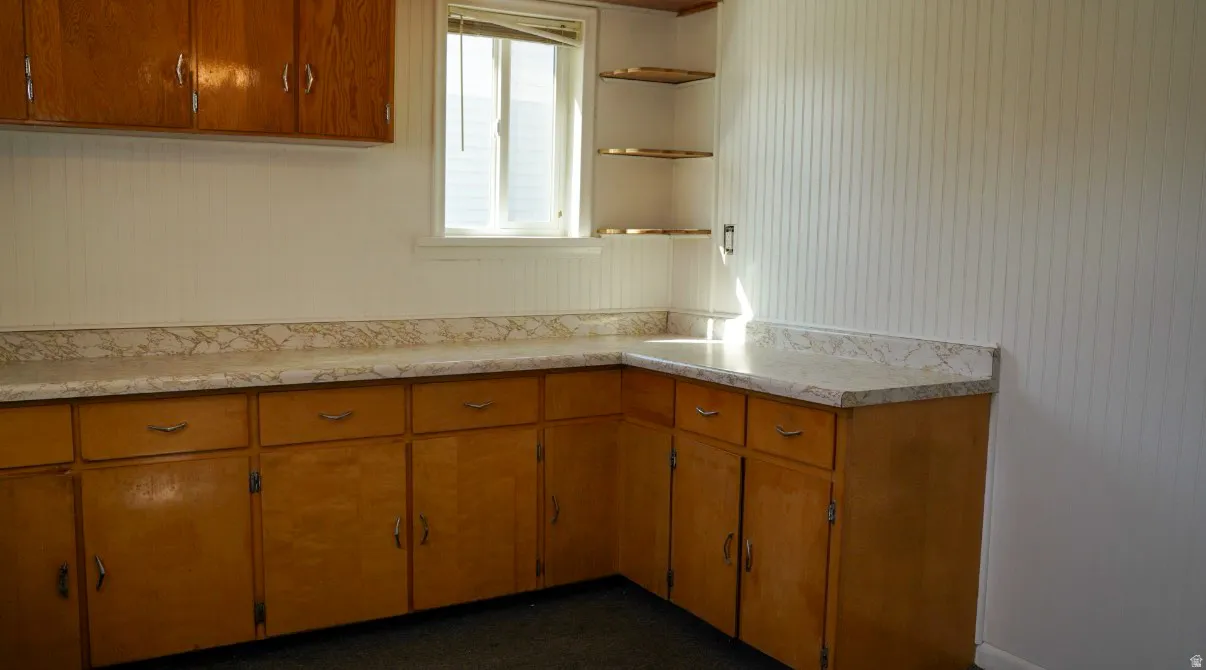 Kitchen with wood finish cabinets, light countertops, and open shelves