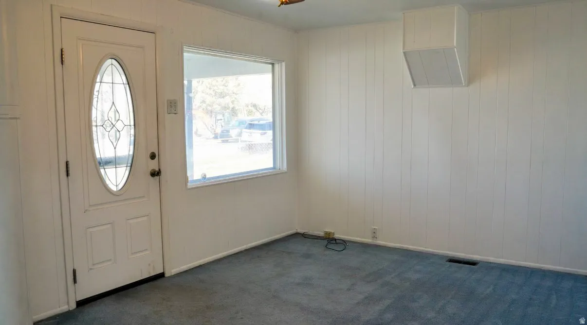 Entryway featuring dark carpet and wooden walls