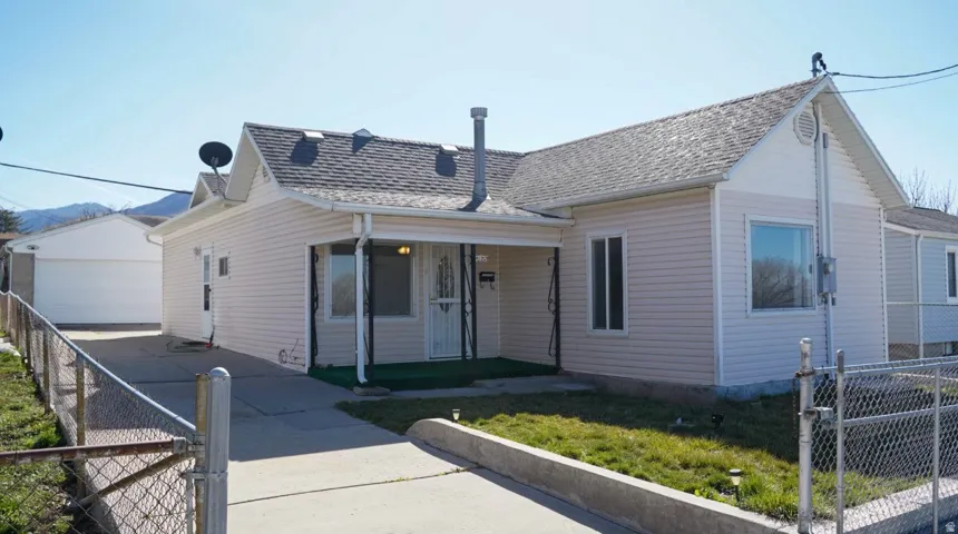 View of front of property with a fenced front yard, a gate, an outbuilding, and a porch