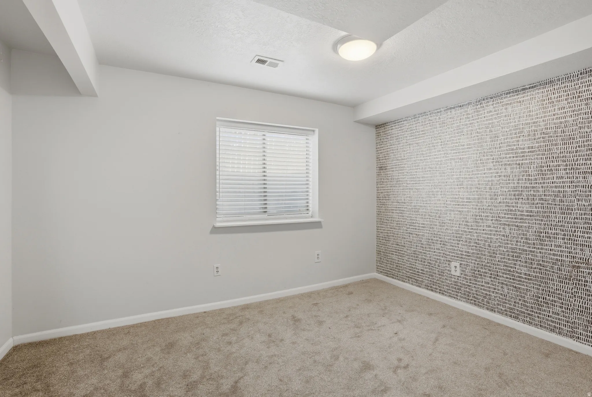 Carpeted spare room featuring brick wall, an accent wall, and a textured ceiling