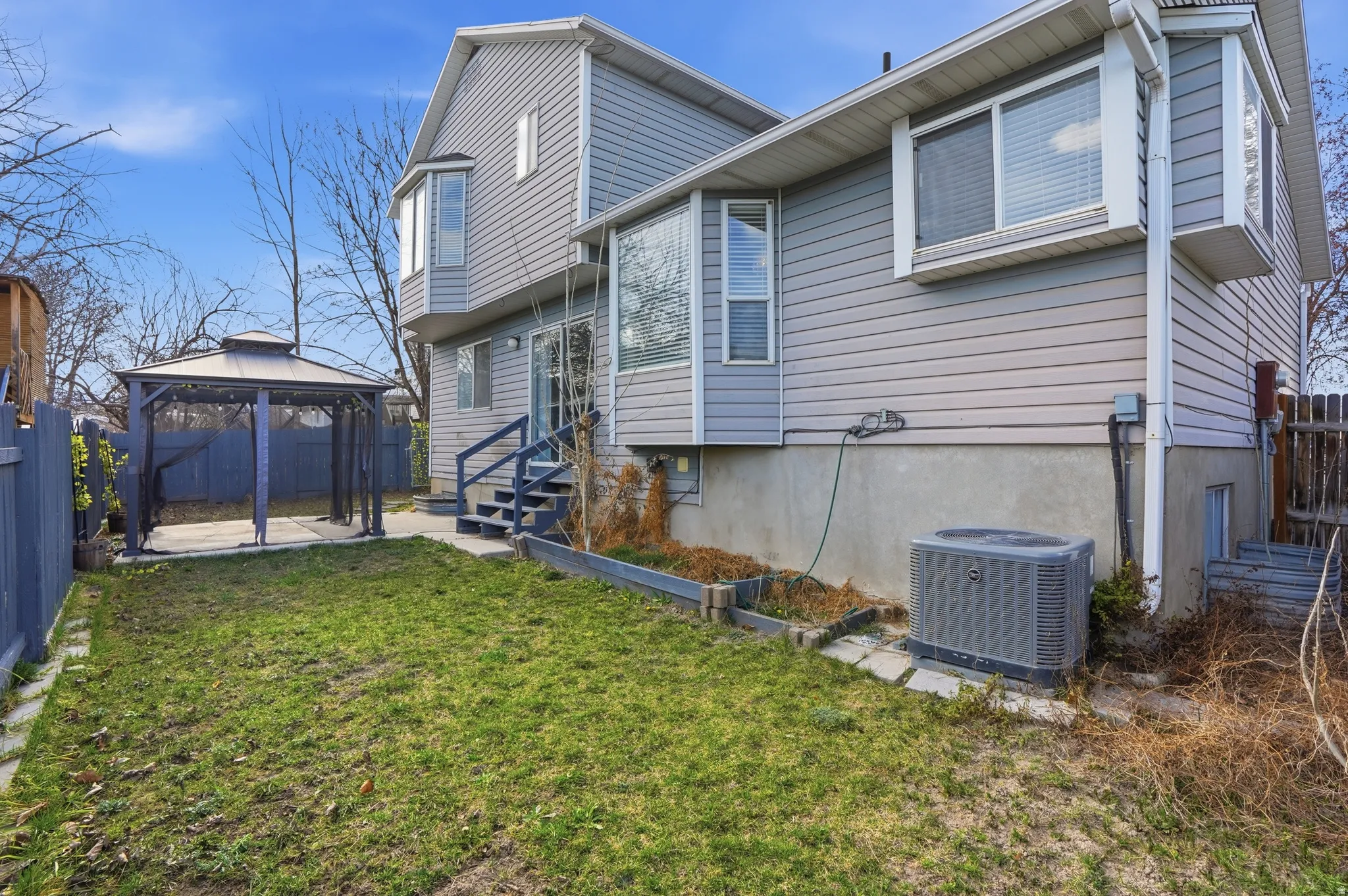 Back of house featuring a fenced backyard, a gazebo, a patio area, and entry steps