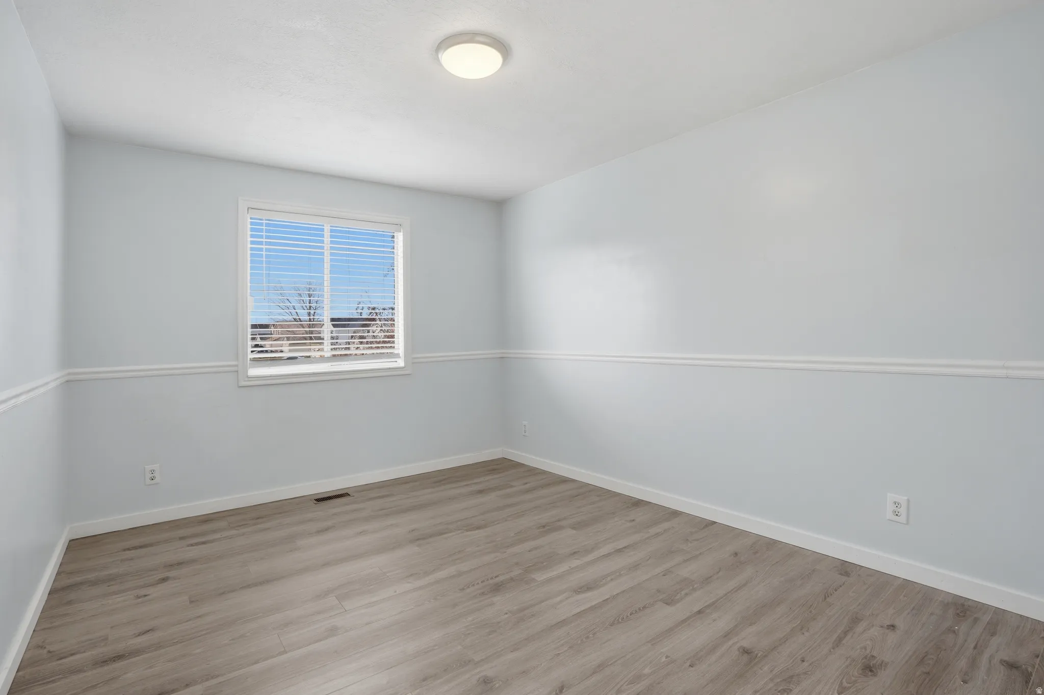 Spare room featuring light wood-type flooring and baseboards