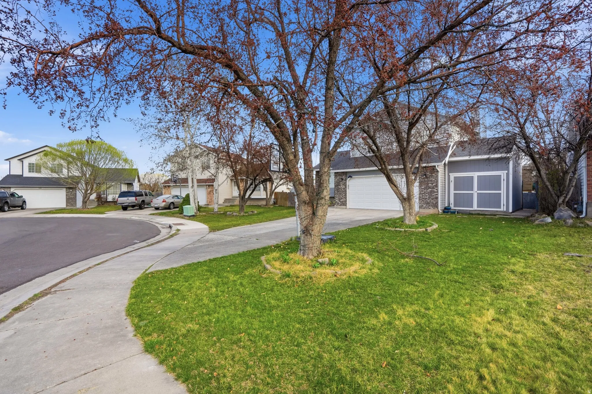 View of front facade featuring driveway, a garage, a residential view, brick siding, and a front yard