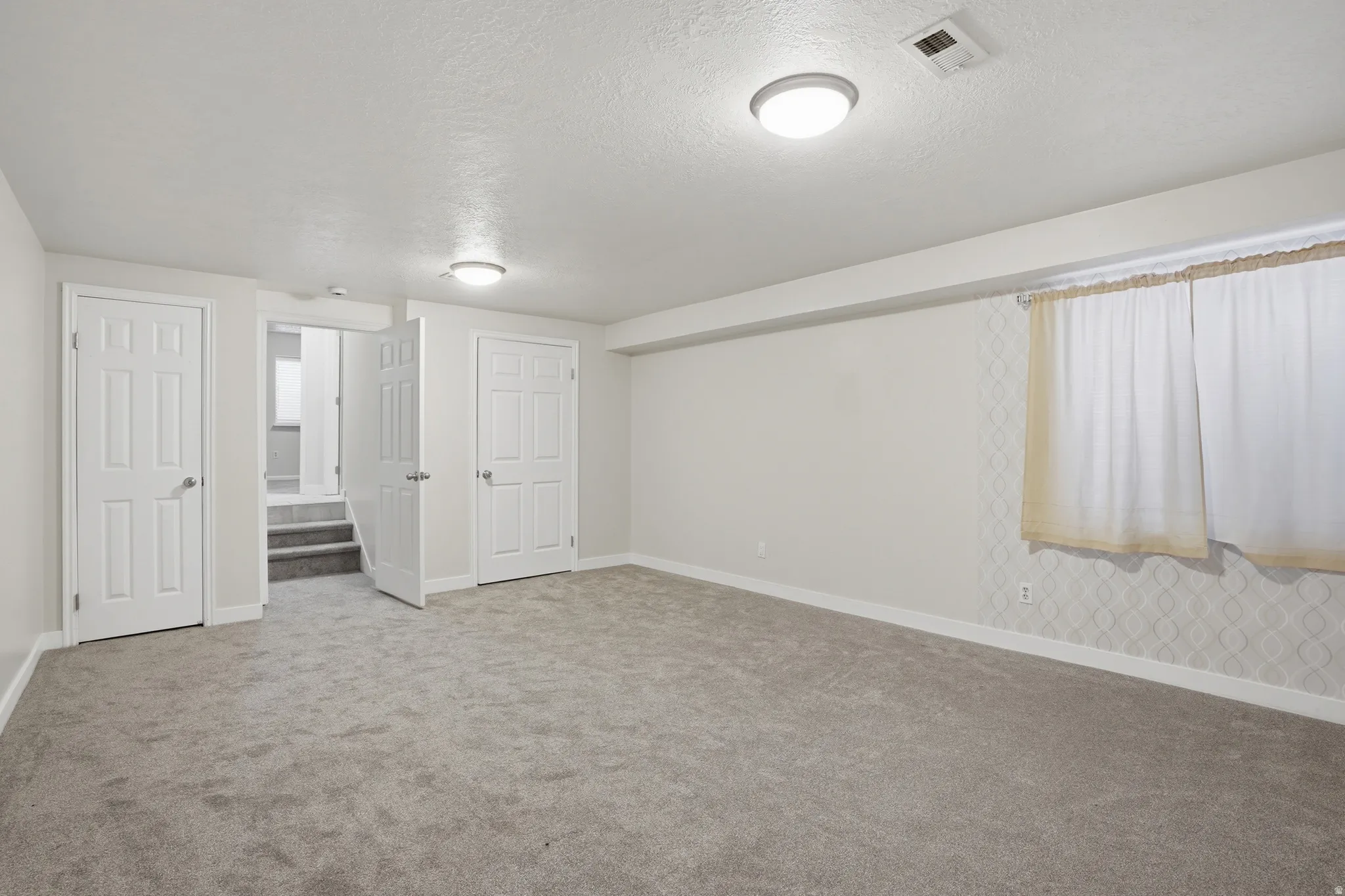 Unfurnished bedroom featuring a textured ceiling, carpet floors, and connected bathroom