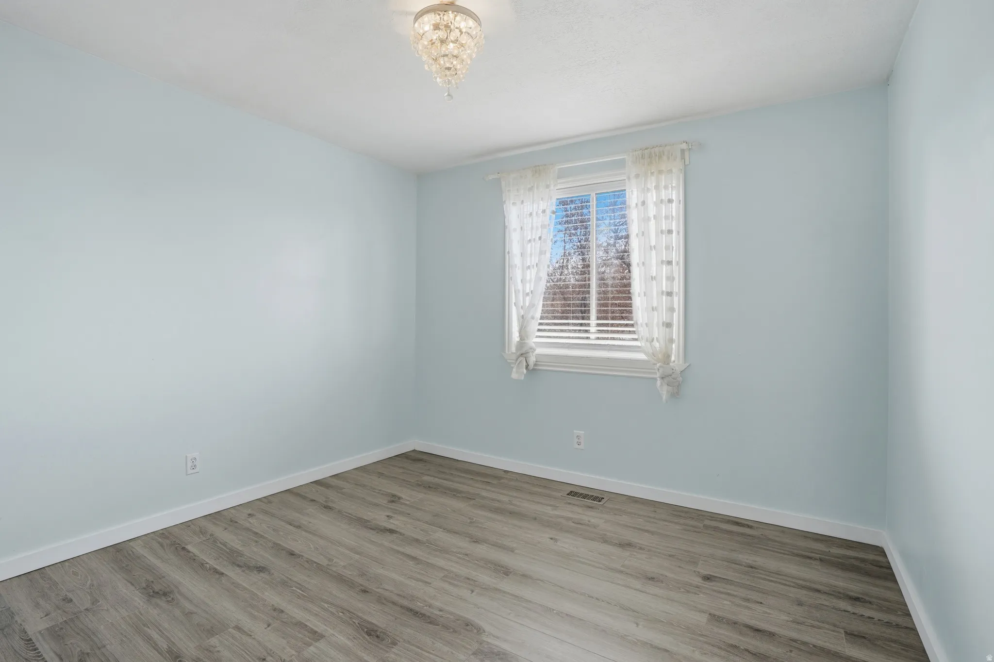 Spare room featuring light wood finished floors and baseboards