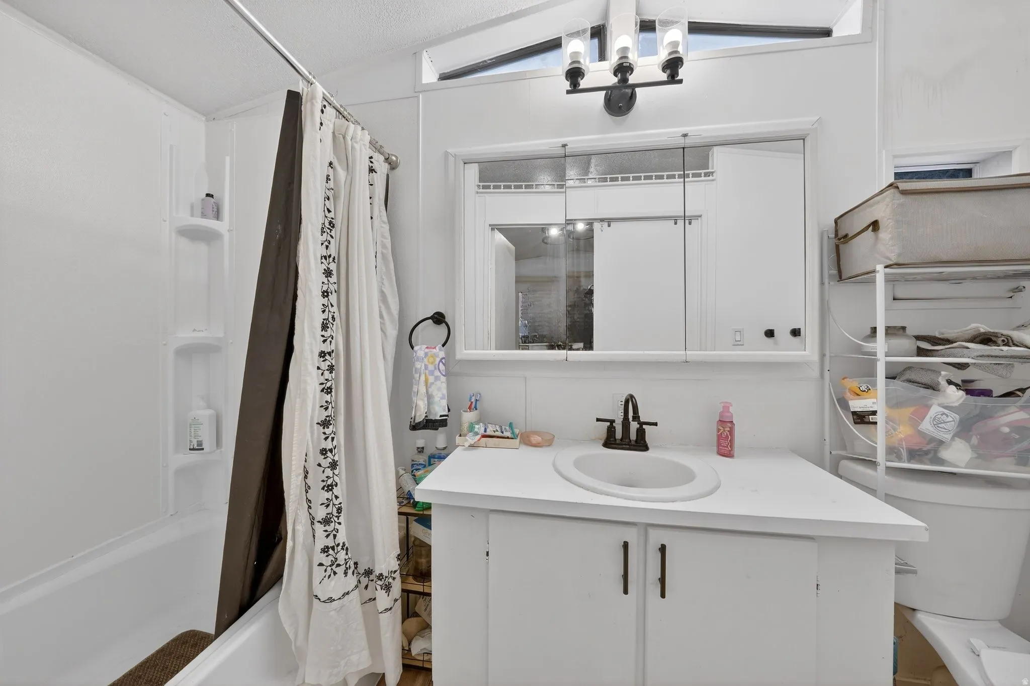 Bathroom with vanity, shower / bath combination with curtain, and lofted ceiling