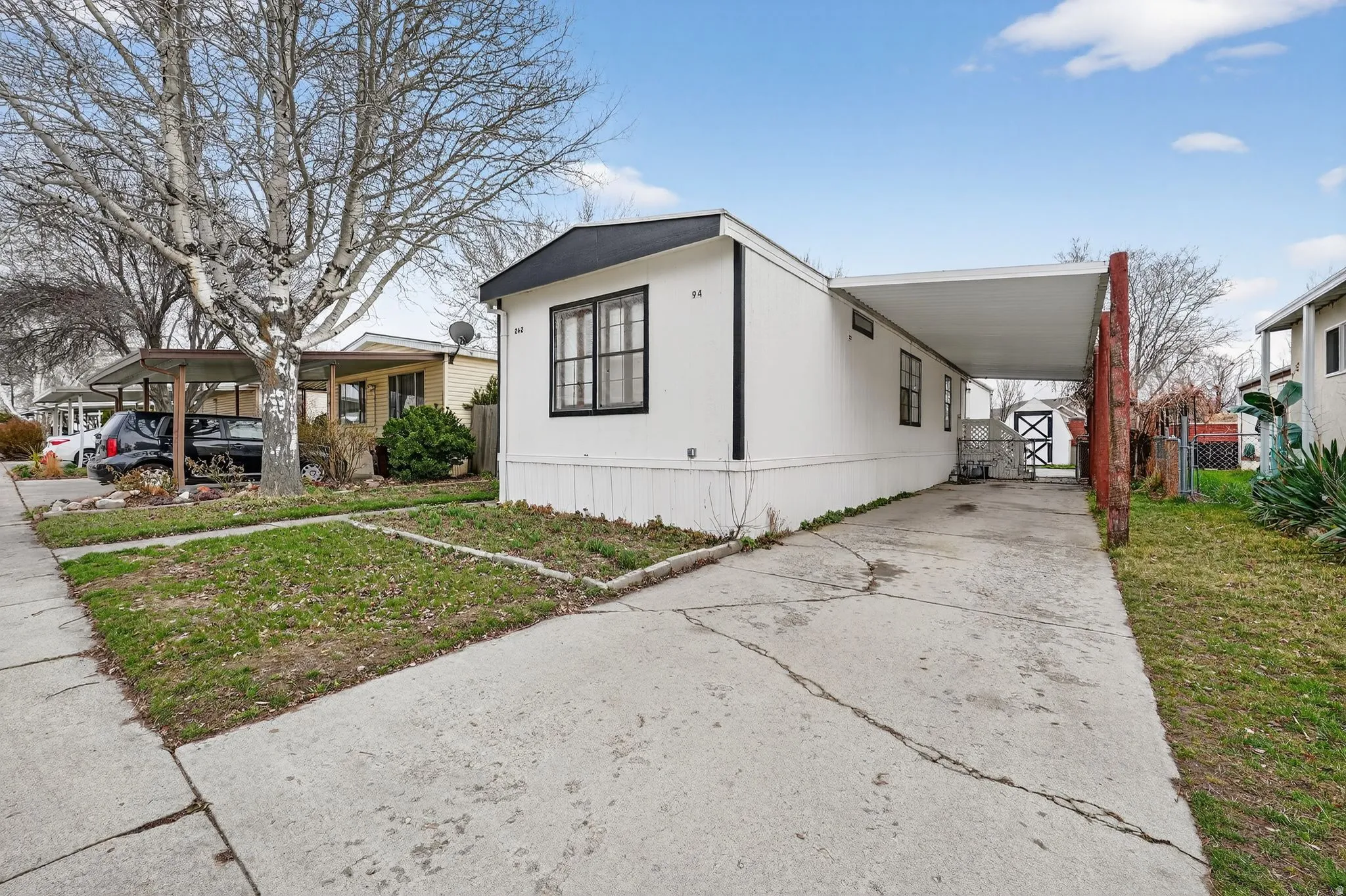 View of front of home with concrete driveway, an attached carport, and a porch