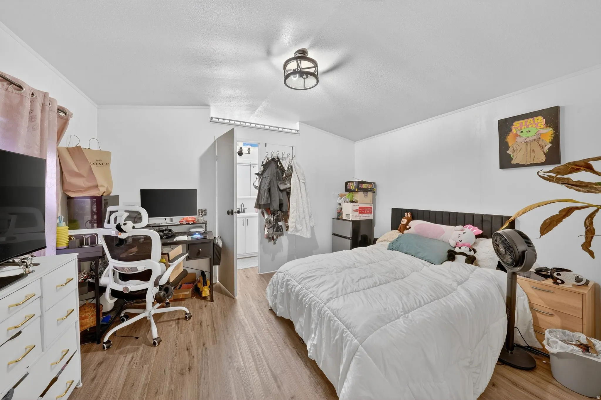 Bedroom with a desk, light wood finished floors, lofted ceiling, and freestanding refrigerator
