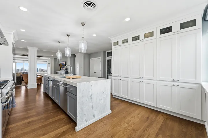 Dual tone kitchen with stainless steel appliances, hanging light fixtures, glass fronted cabinets, dark wood-style floors, and dual tone cabinetry