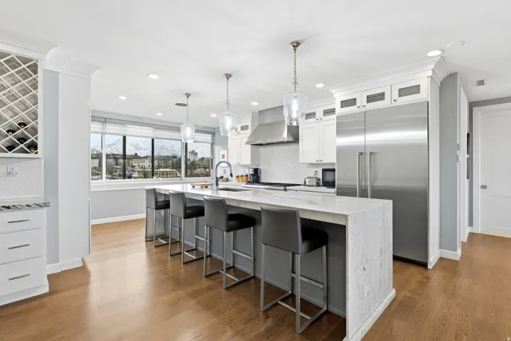 Kitchen with built in fridge, light stone counters, tasteful backsplash, and a kitchen breakfast bar