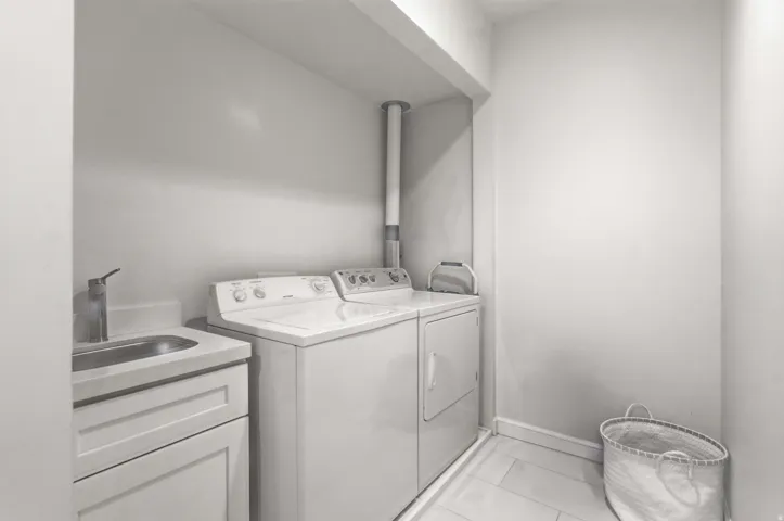 Laundry area with independent washer and dryer and light tile patterned floors