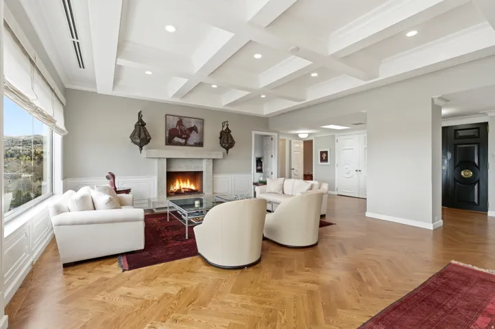 Living room featuring parquet flooring, a premium fireplace, coffered ceiling, crown molding, and recessed lighting