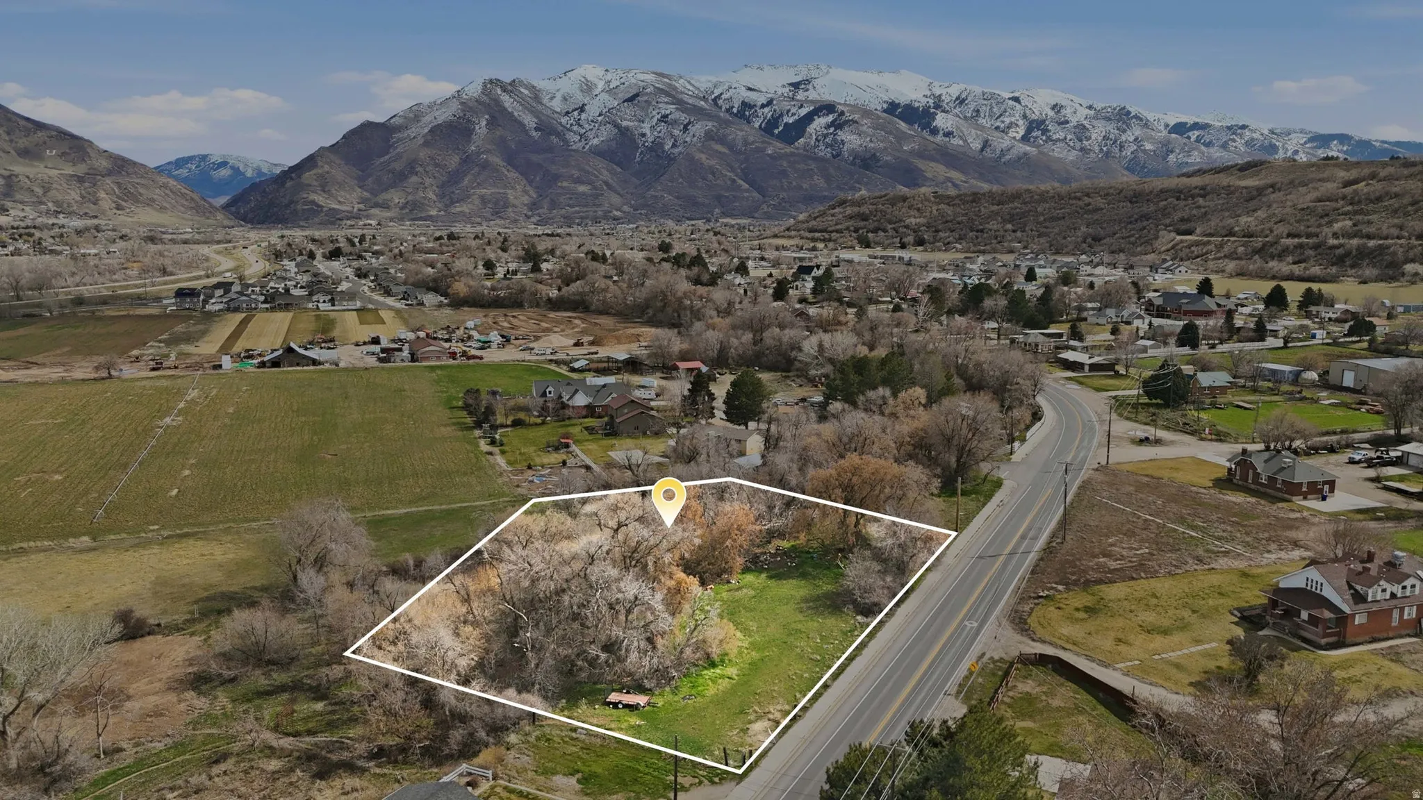 Overview of rural landscape featuring property parcel outlined, mountains, and nearby suburban area
