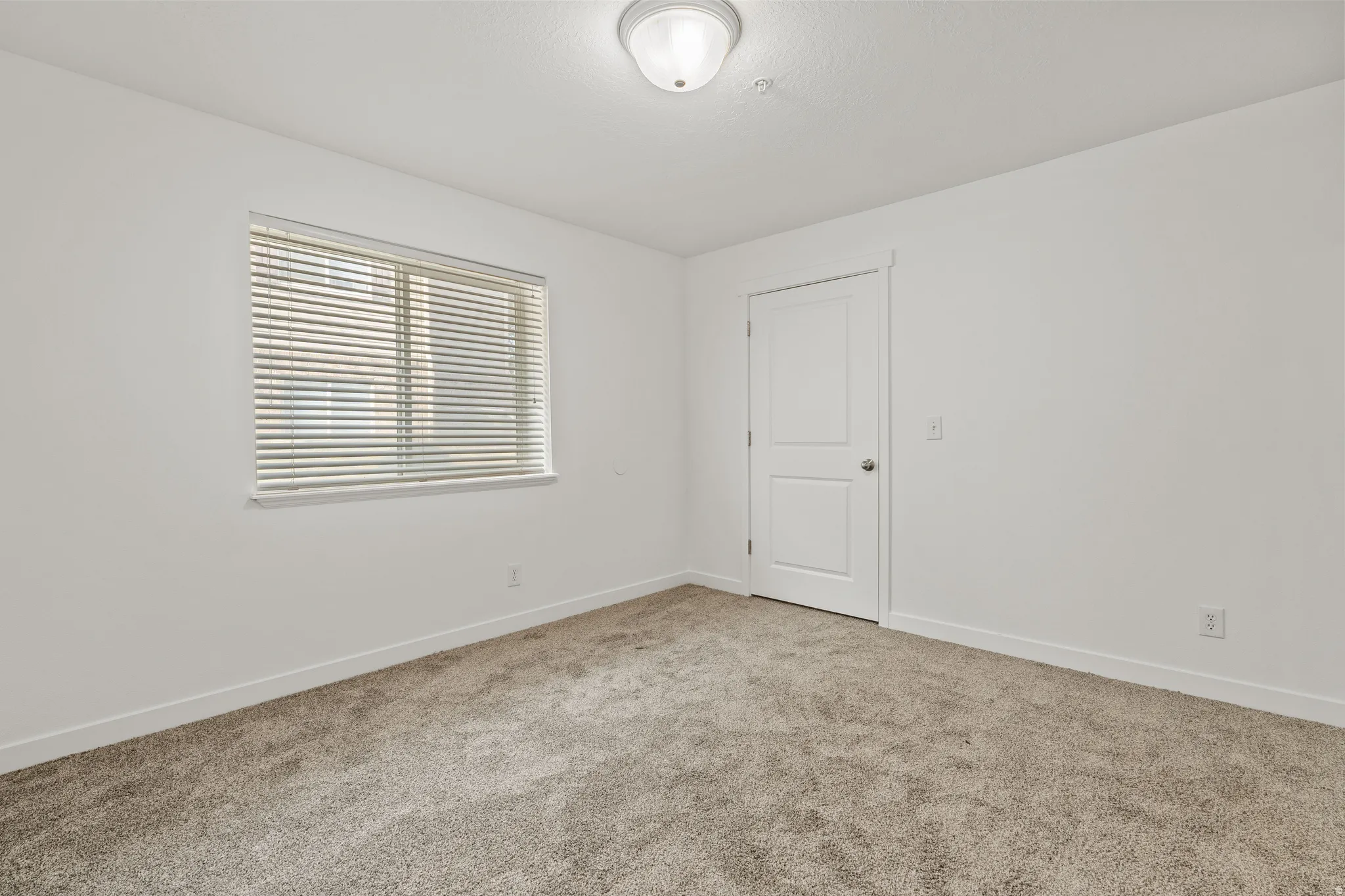 Carpeted spare room featuring baseboards