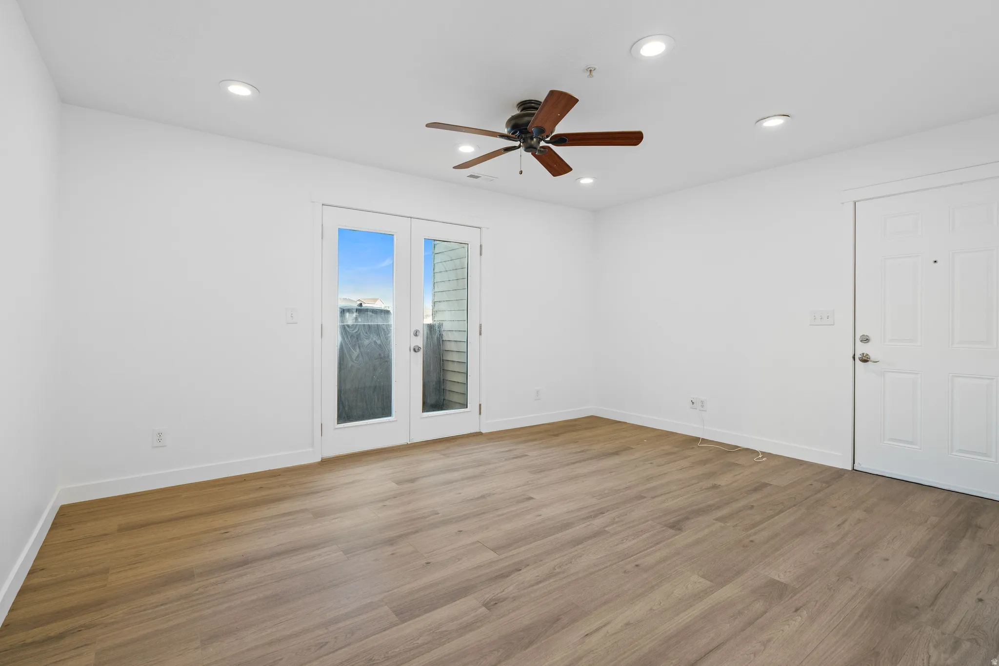 Empty room featuring french doors, a ceiling fan, wood finished floors, and recessed lighting
