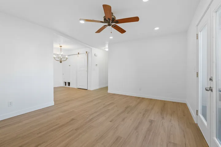 Unfurnished living room with ceiling fan, light wood-style flooring, and hanging lights