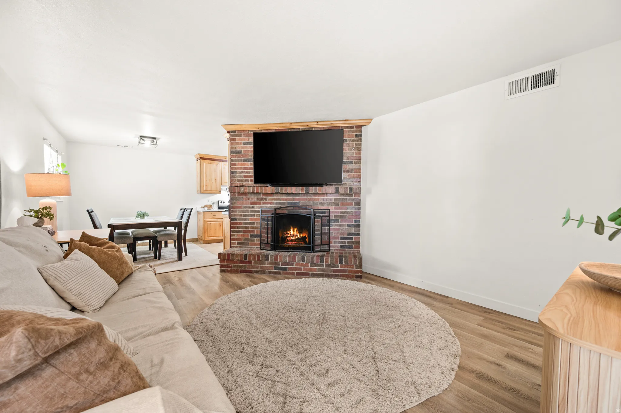 Living room with light wood-type flooring and a brick fireplace