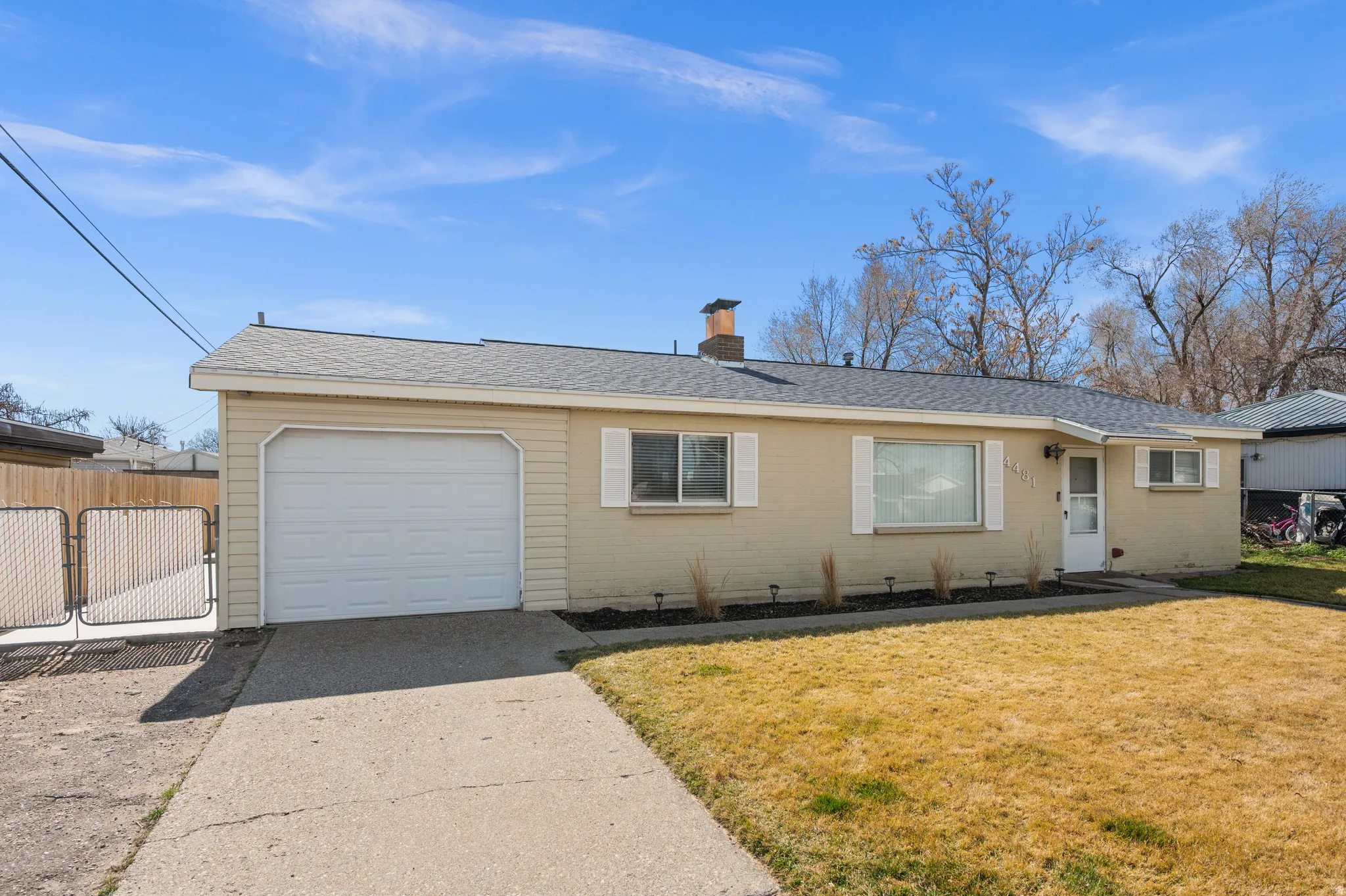 Ranch-style home with a shingled roof, a garage, a chimney, concrete driveway, and a front lawn