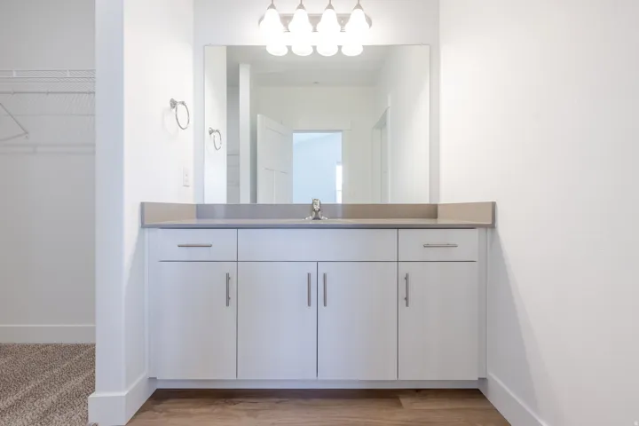 Single vanity with a light countertop, integrated sink, and white cabinetry