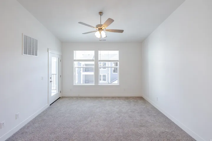 Recessed lighting, ceiling fan with integrated lighting, expansive windows with blinds, glass-paneled door, and neutral-toned carpeting