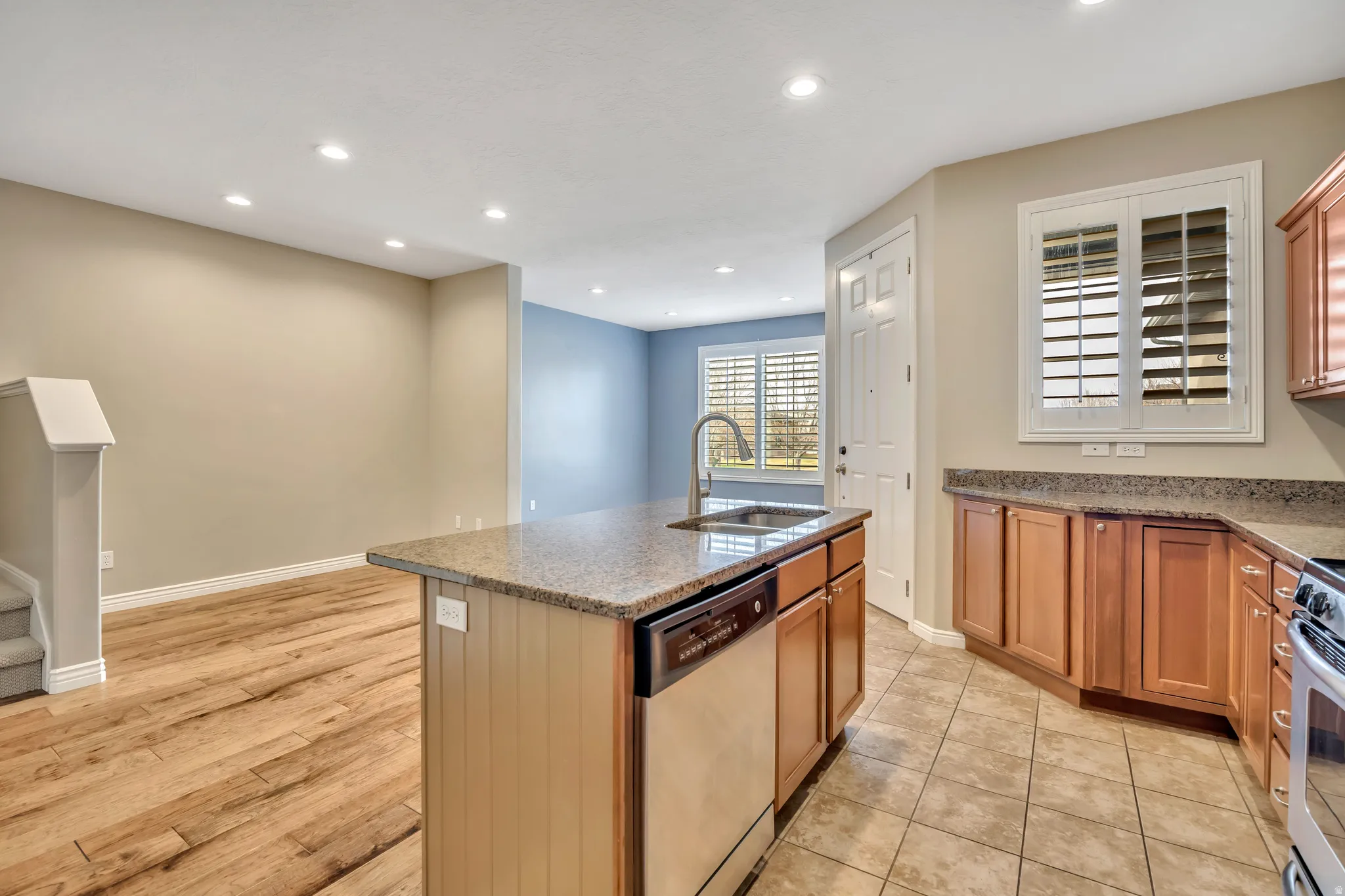 Kitchen with dark stone counters, stainless steel appliances, a kitchen island with sink, recessed lighting, and light wood finished floors