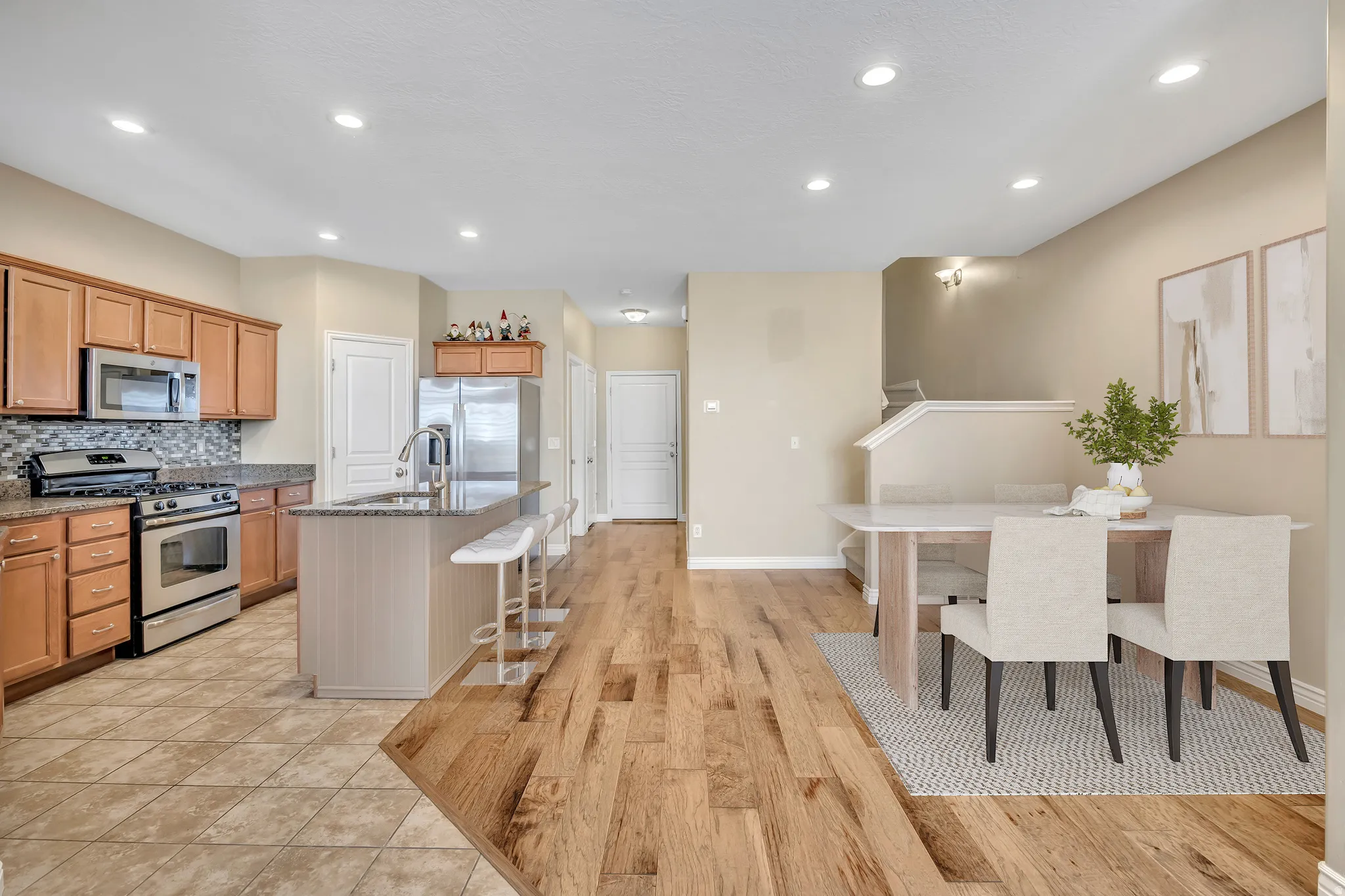 Kitchen with stainless steel appliances, a kitchen bar, light wood-style floors, decorative backsplash, and dark stone counters