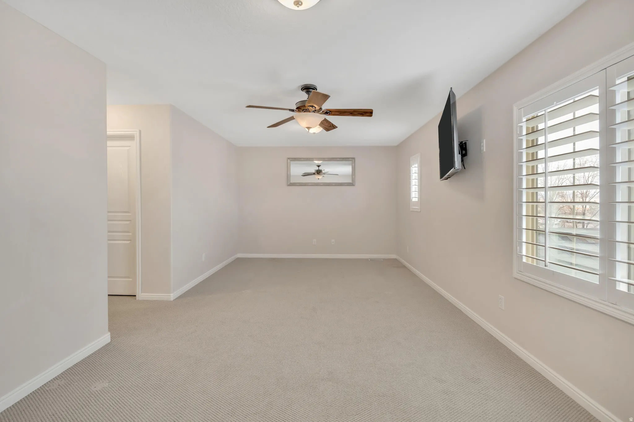 Unfurnished room featuring light colored carpet and a ceiling fan