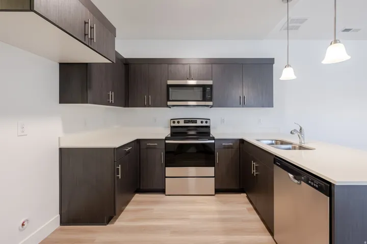 U-shaped kitchen with dark wood-finish cabinetry, light countertops, and wood-finish flooring