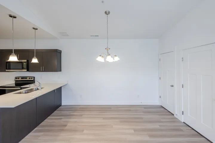 Kitchen featuring dark wood-finish cabinetry, stainless steel microwave, electric range, and a dual basin sink