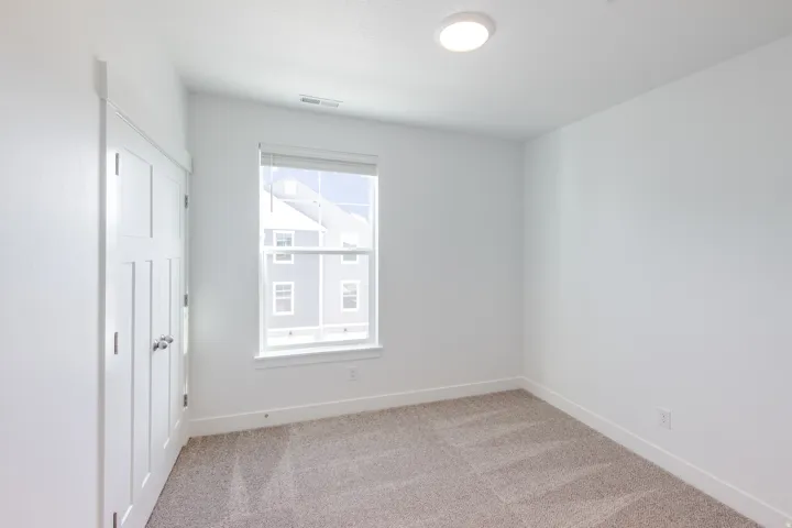 Neutral-toned carpeting, white walls, and a window with a white frame