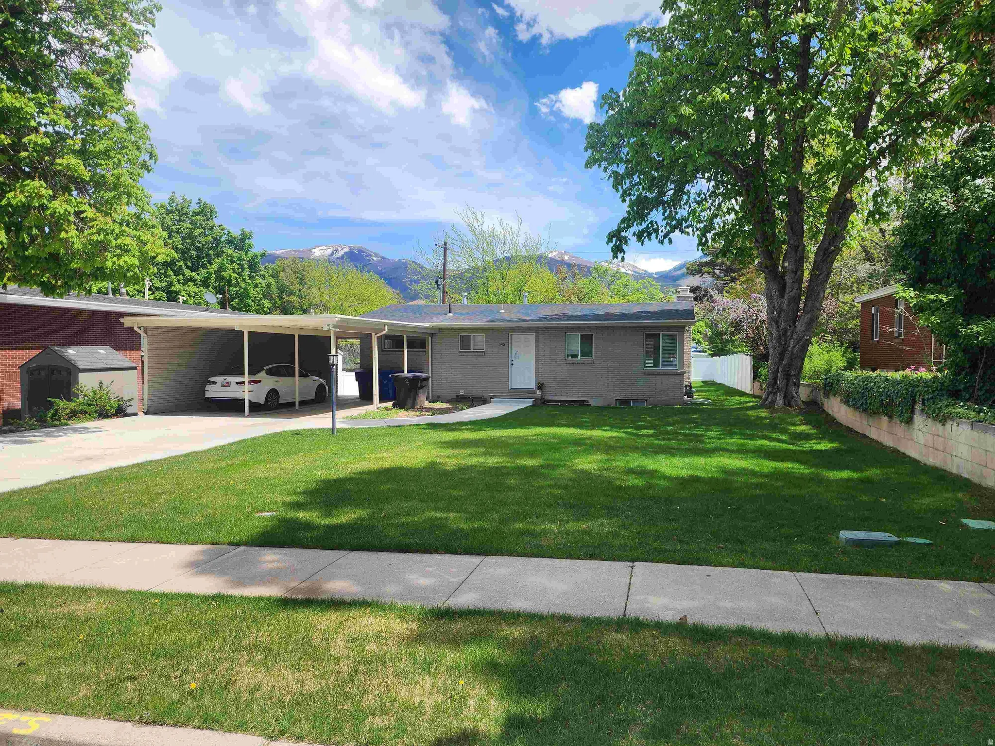 Single story home featuring a carport, brick siding, a mountain view, and concrete driveway