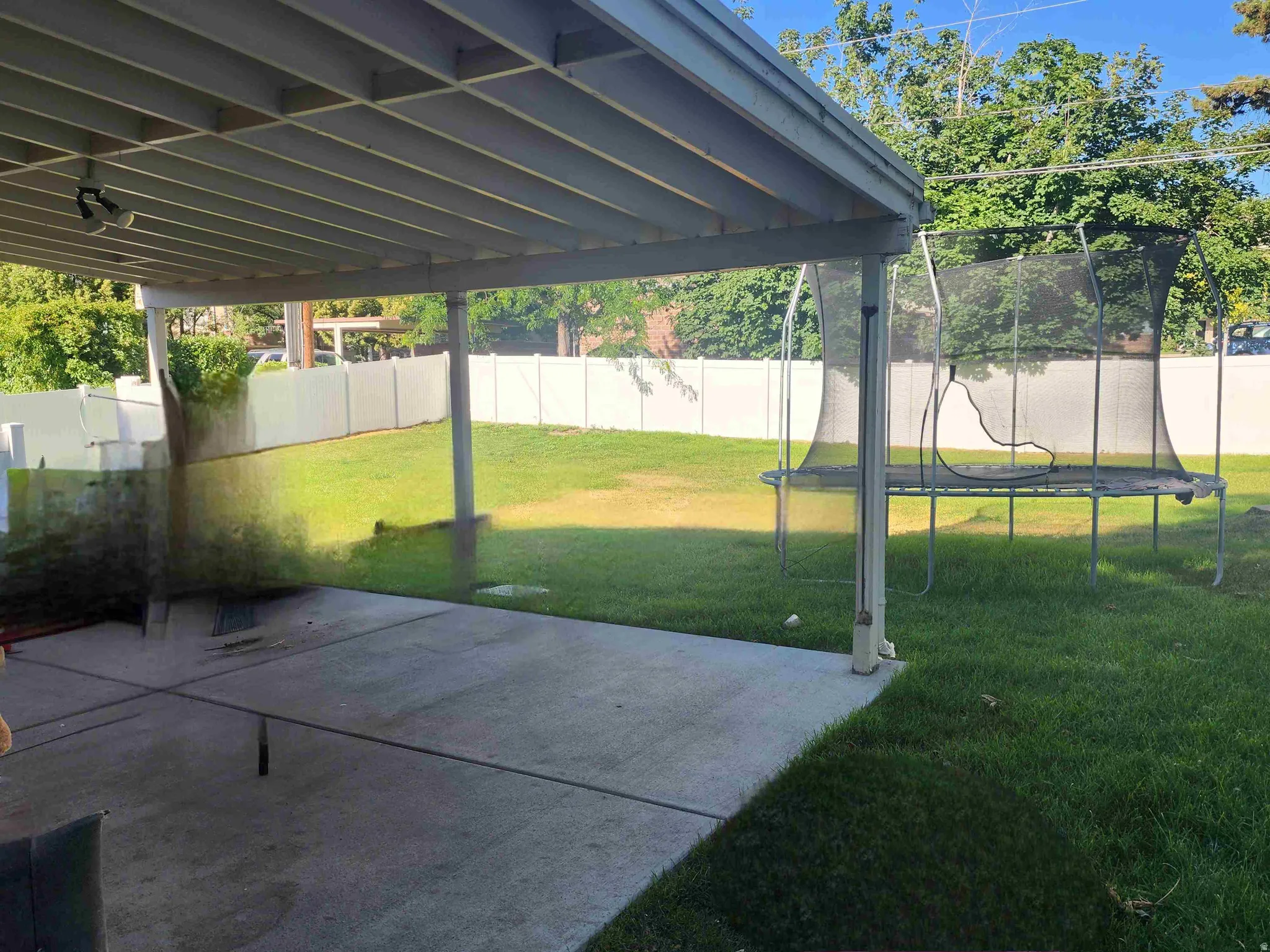 Fenced backyard with a trampoline and a patio area
