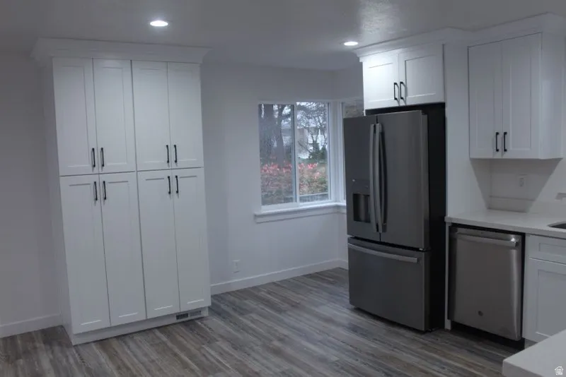 Kitchen featuring stainless steel appliances, white cabinets, light wood finished floors, recessed lighting, and light stone countertops