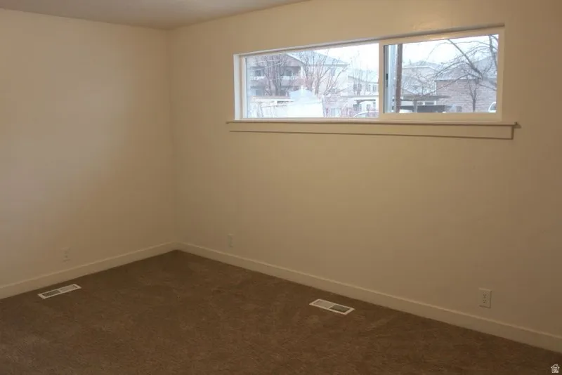 Spare room with baseboards and dark carpet