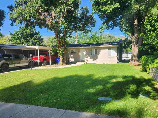 Ranch-style house featuring a front lawn, an attached carport, brick siding, and a chimney