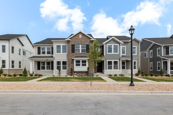 Townhouse exterior featuring a covered porch entrance, dark shingle roof, bay window, and a blend of brick and horizontal siding finishes