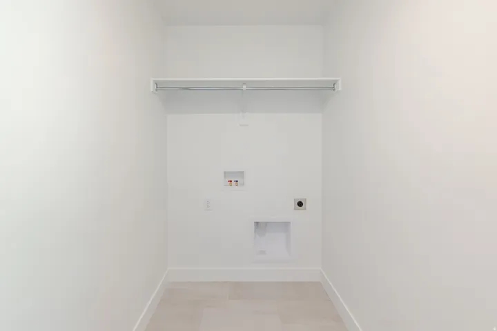 Dedicated laundry area featuring a white storage shelf and hanging rod